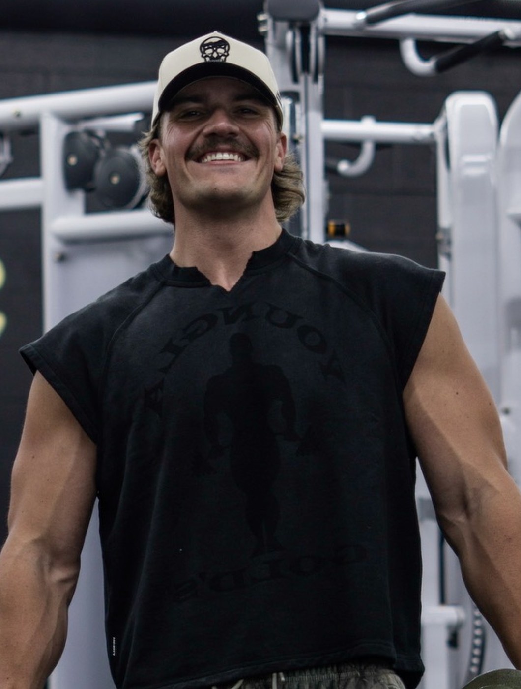JJ Loveland now, lean and muscular, holding dumbbells in the gym.